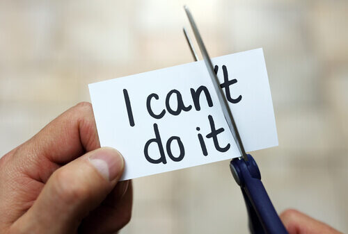 Hands cutting a card that reads 'I can't do it'