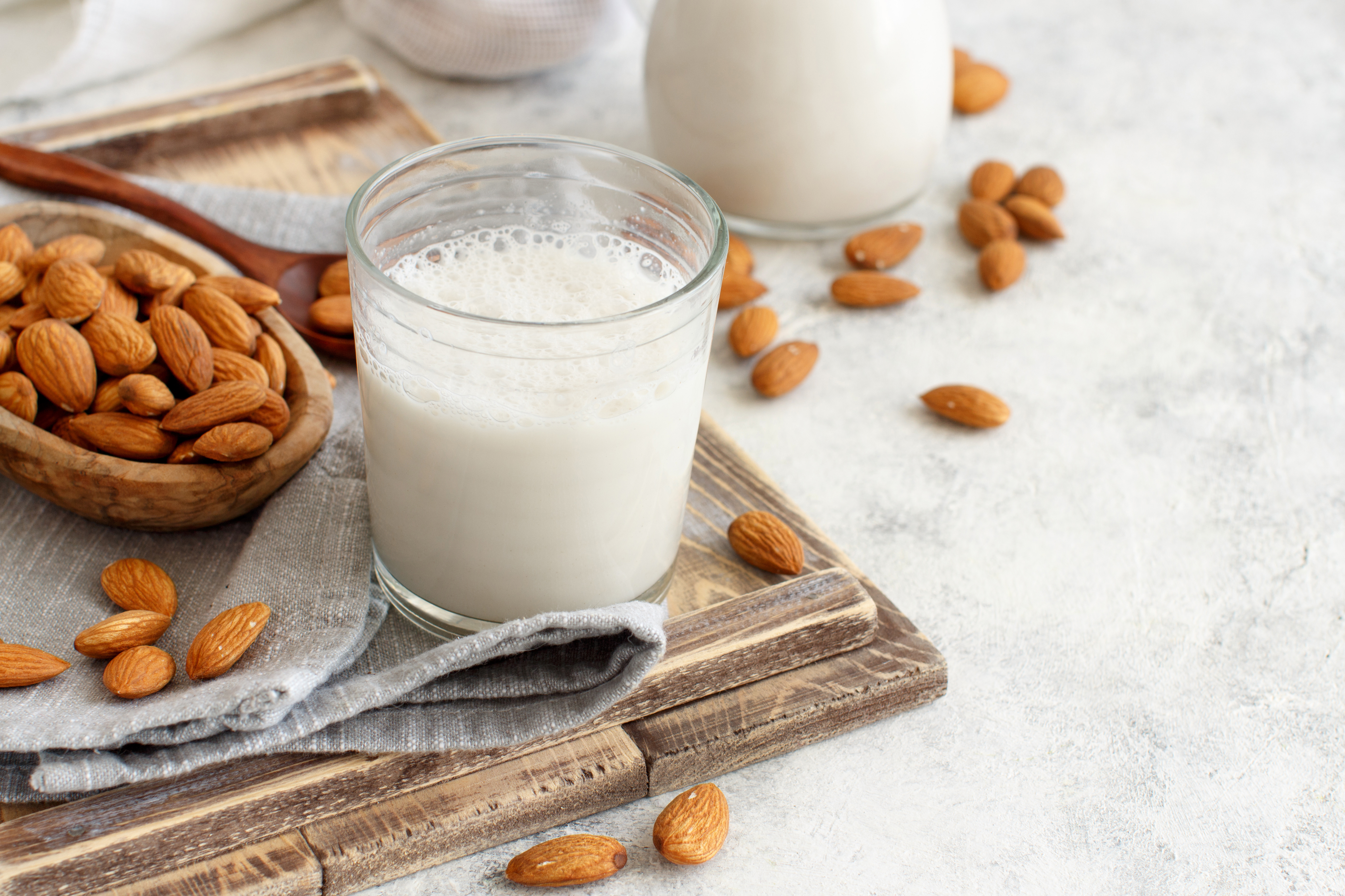 Glass of almond milk with almonds on a wooden board