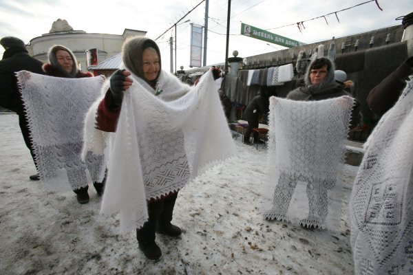 Vendors selling white knitted shawls at an outdoor market