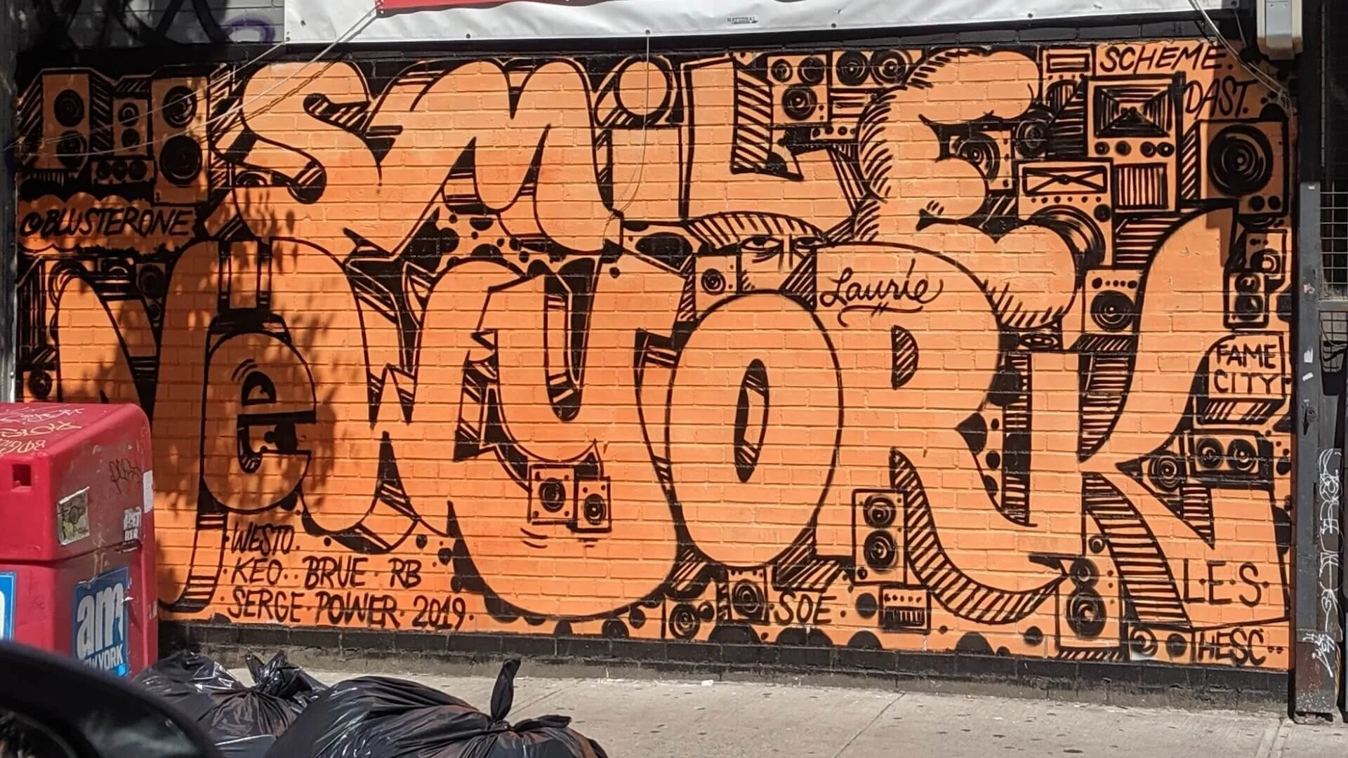 Orange brick-wall mural reading Smile New York with boombox illustrations, Lower East Side