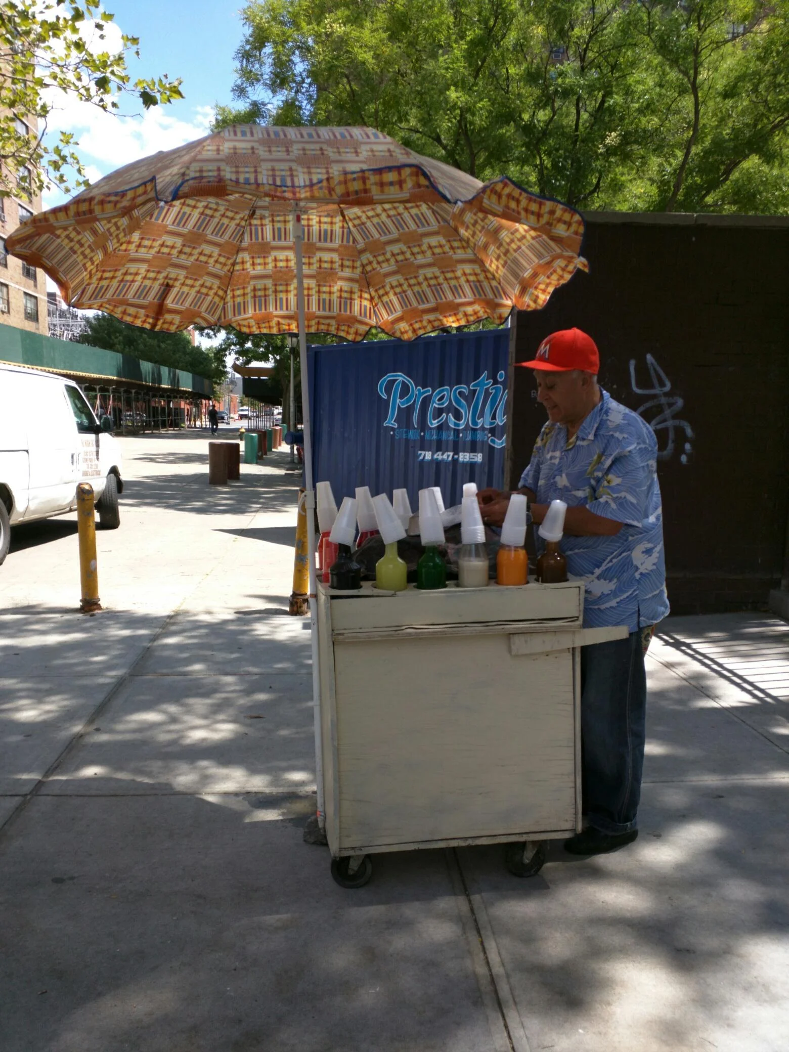 Street vendor with an umbrella cart selling drinks on an NYC sidewalk