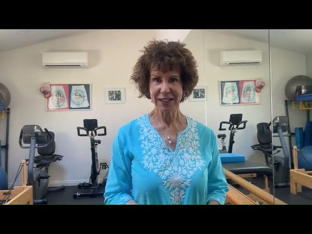 Lori Michiel in a teal top standing in her fitness studio