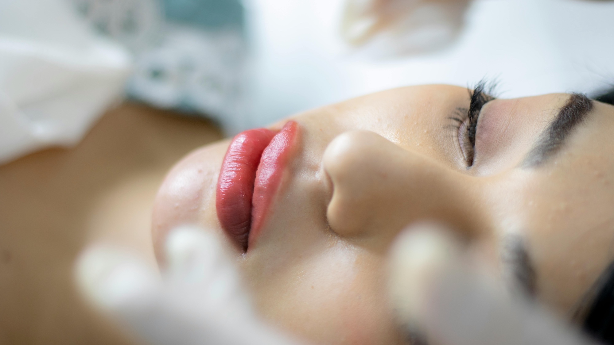 Close-up of a client resting with freshly tattooed lip blush during a procedure