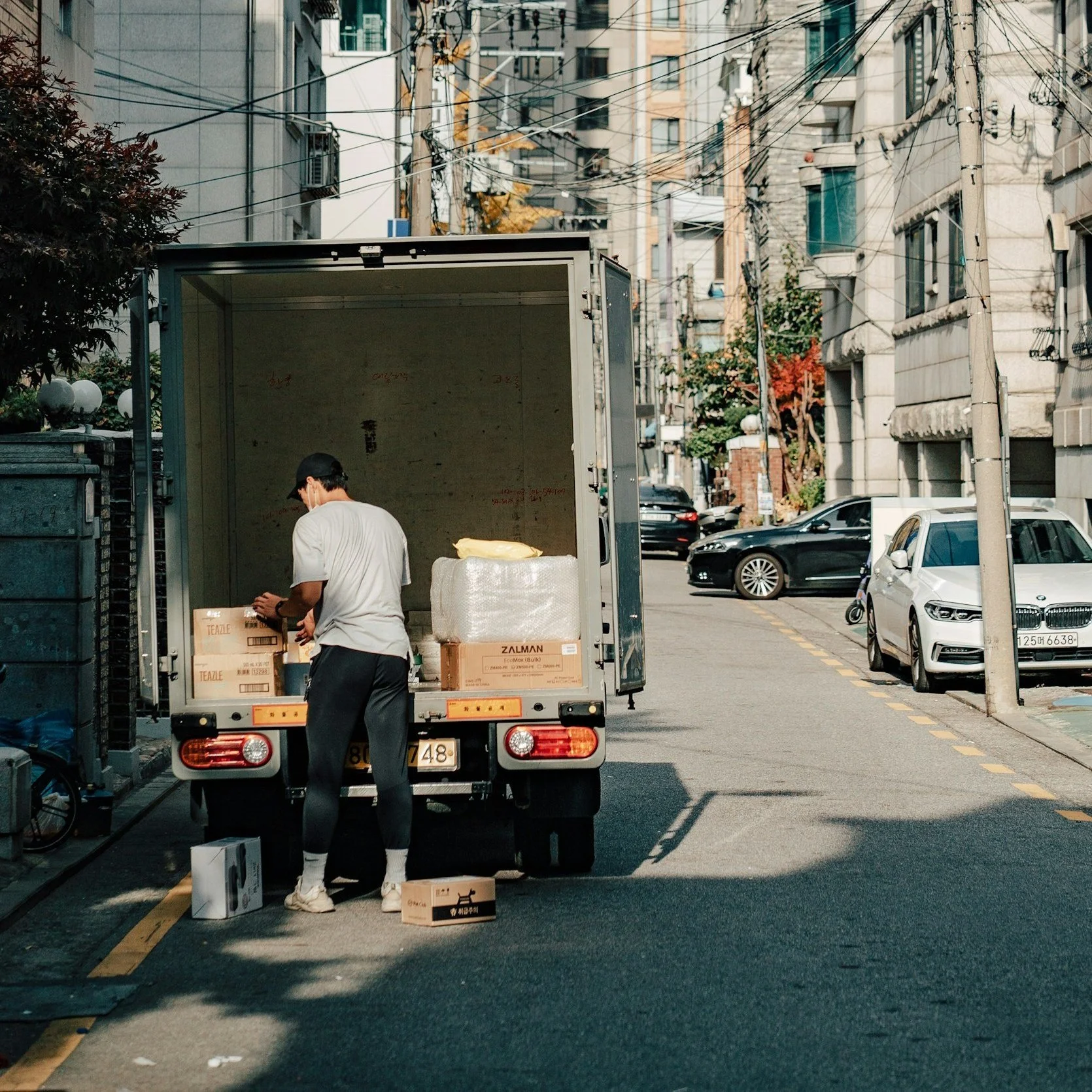 A delivery worker unloading boxes from the back of a small truck on a city street