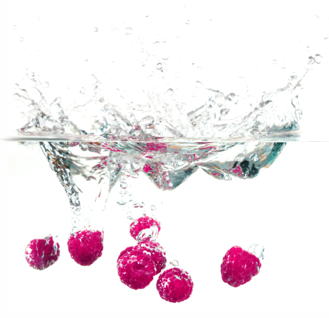 Raspberries splashing into clear water
