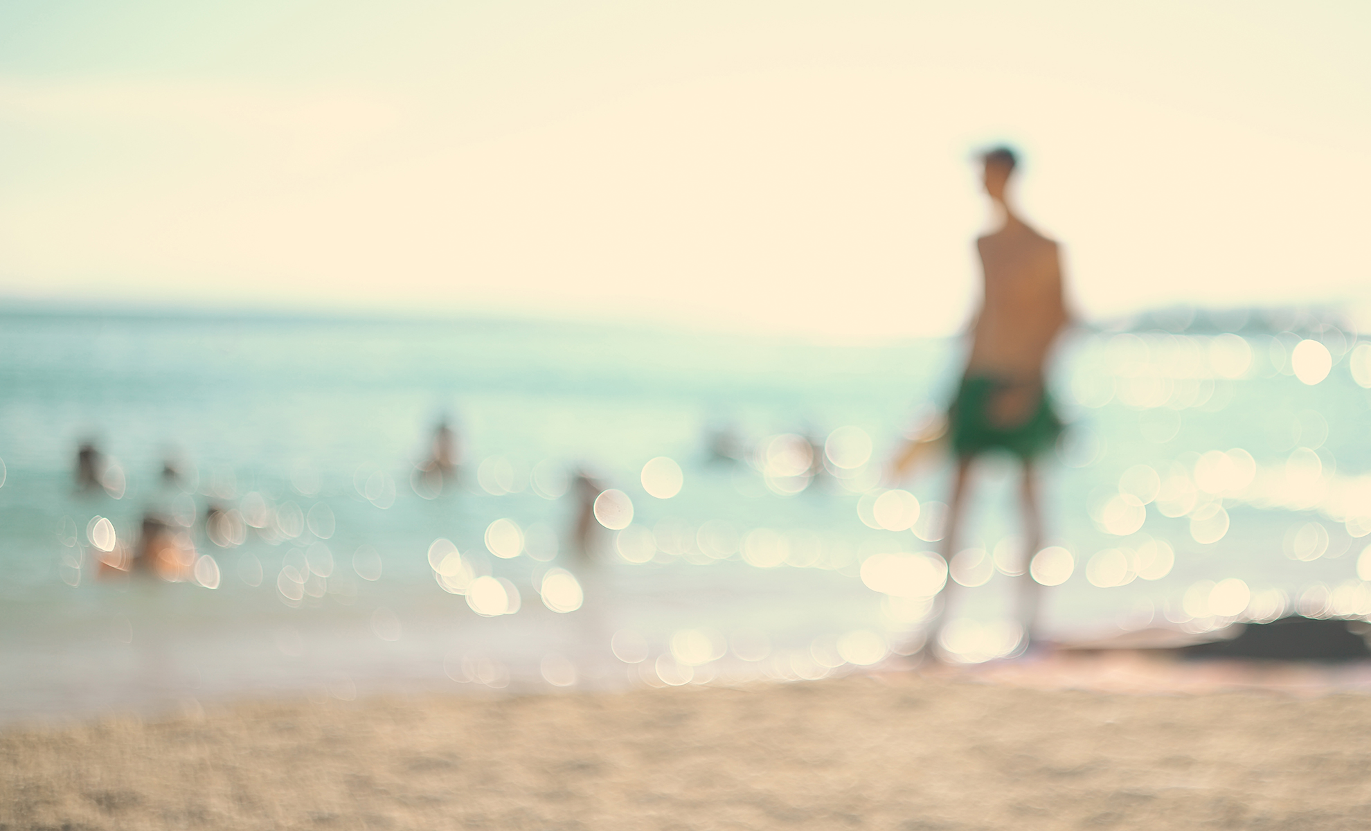 Soft-focus teal water at the beach's edge with warm bokeh light