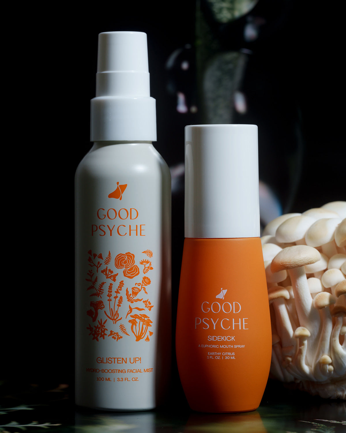 Two Good Psyche bottles — Glisten Up facial mist and Sidekick mouth spray — with mushrooms on a dark background.