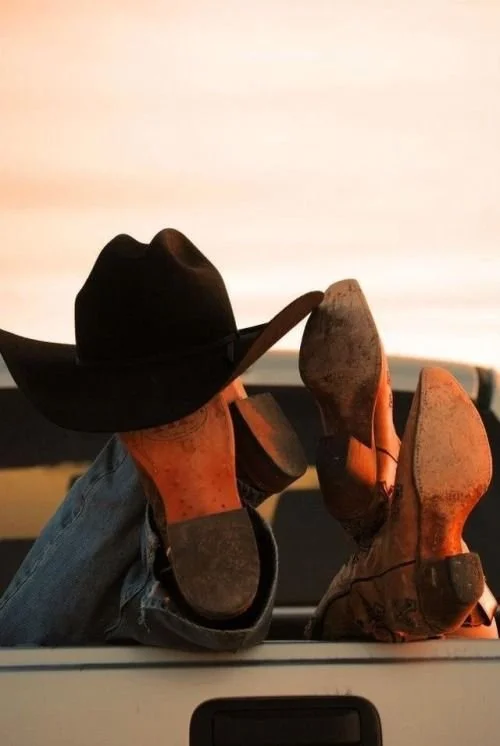 Cowboy boots in the truck bed at sunset.