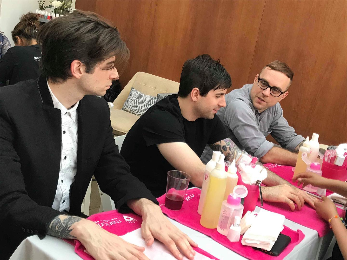 Three men getting manicures with pink MANIORPEDI branded towels