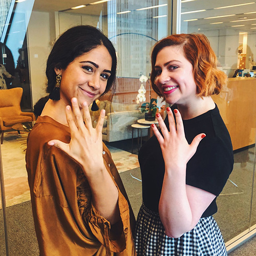 Two women in an office setting showing off freshly painted nails