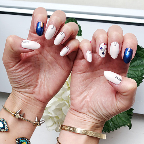 White base manicure with blue glitter accent nails and gem details