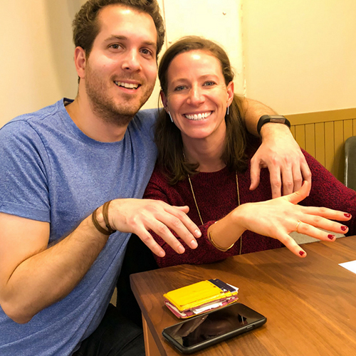 Smiling man and woman at a table showing their freshly painted nails