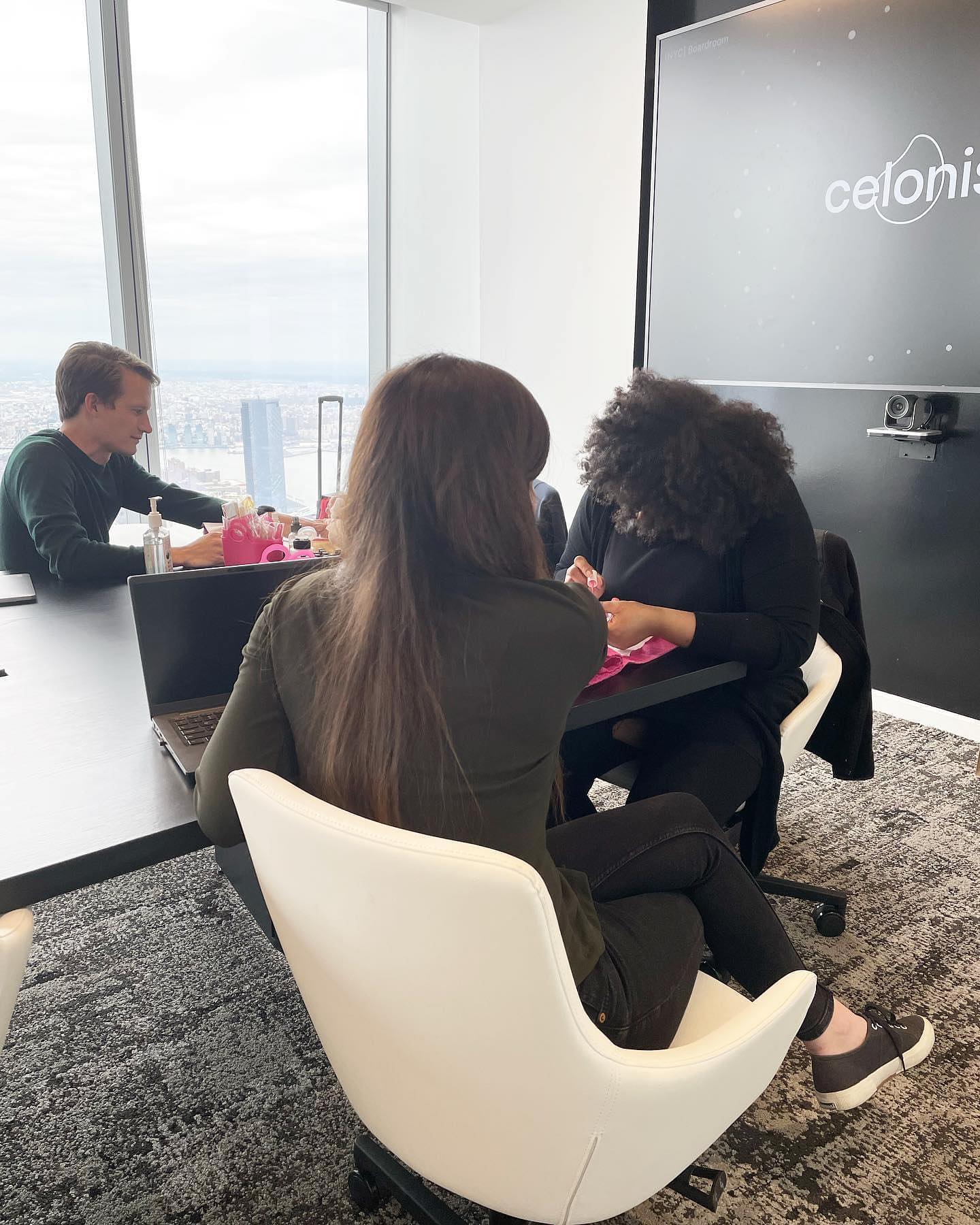 Technician giving manicures in a high-rise conference room with a city skyline view
