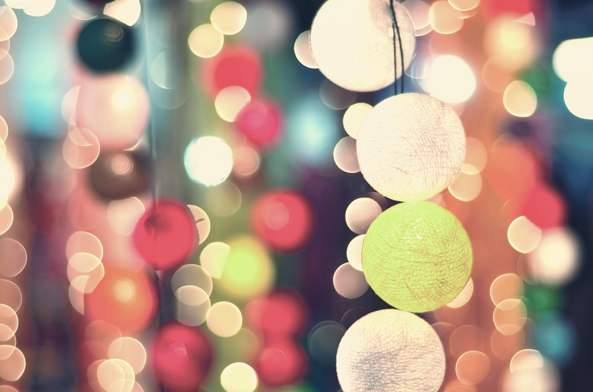 Soft colorful bokeh of hanging round paper lanterns and string lights at a festive gathering