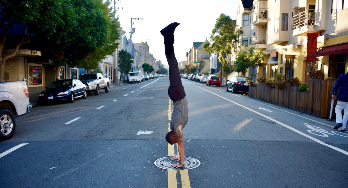 Mark Morford in a handstand in a San Francisco street lined with Victorian houses