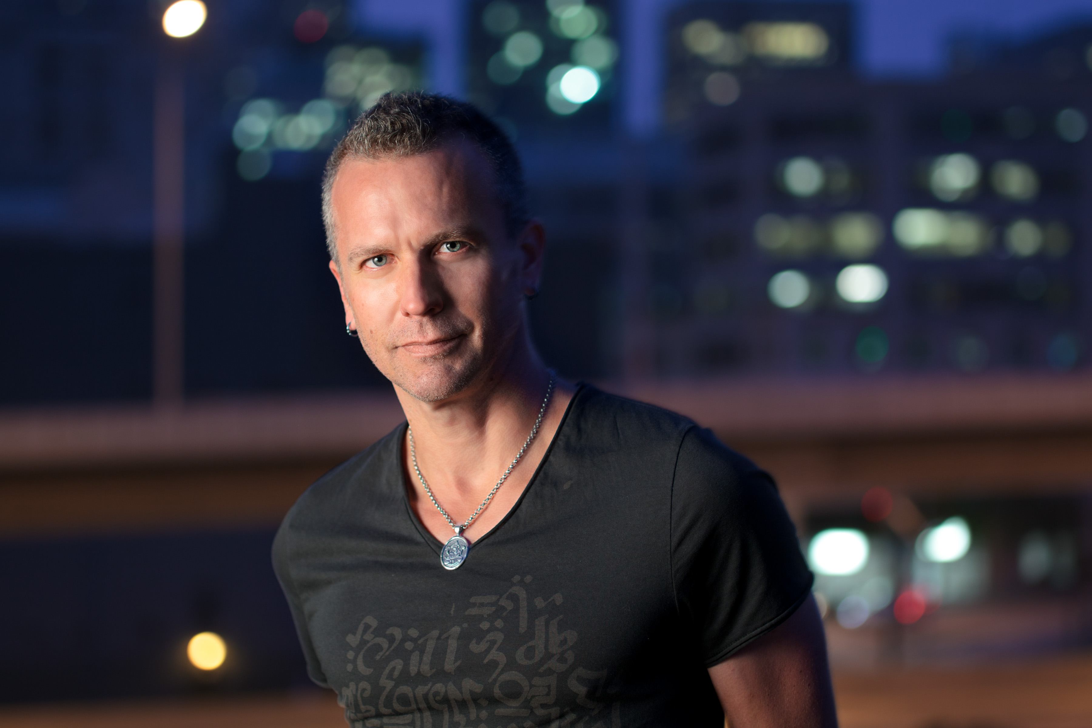 Portrait of Mark Morford with short grey hair against blurred night city lights