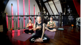 Three people in seated meditation in a darkly lit gothic room