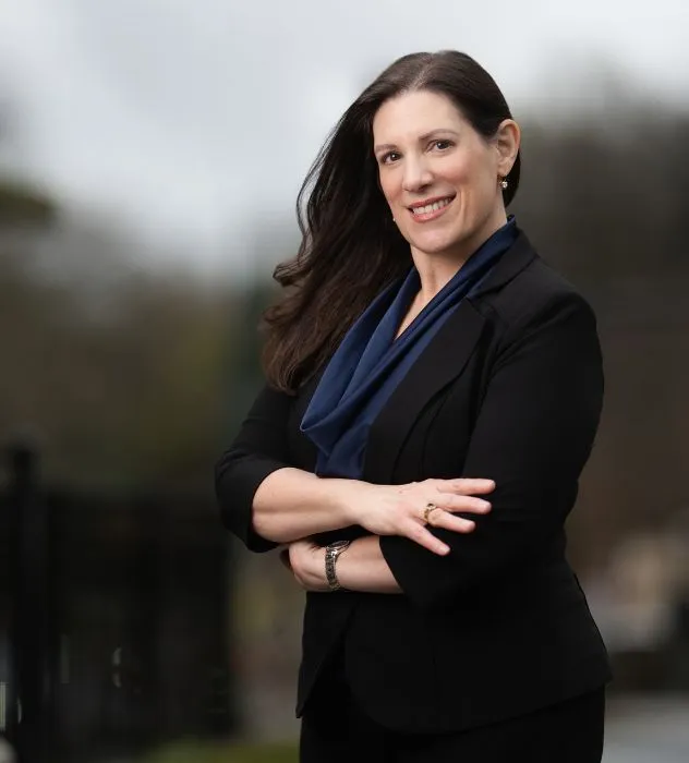 Mary Cioffi outdoors in a black blazer and blue scarf, arms crossed