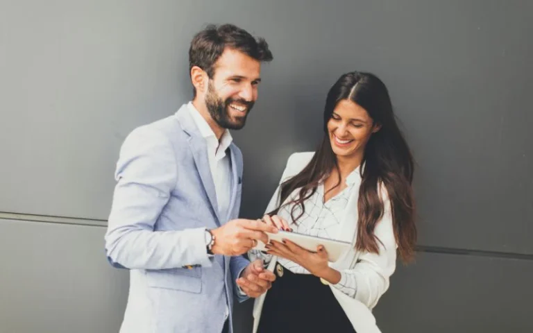 Man and woman in business attire reviewing a tablet together