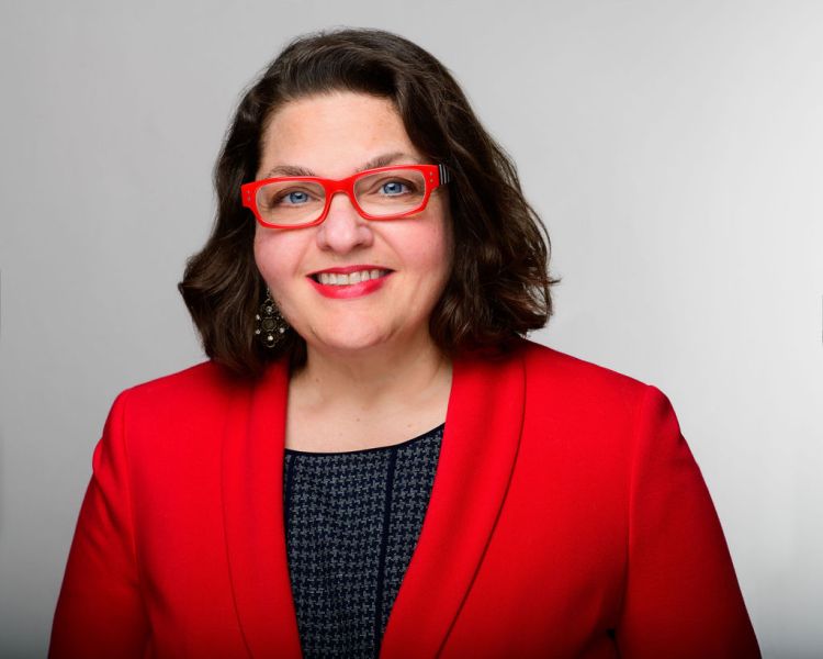 Mary Balistreri, the Mindful Business Coach, in her signature red blazer and red glasses.