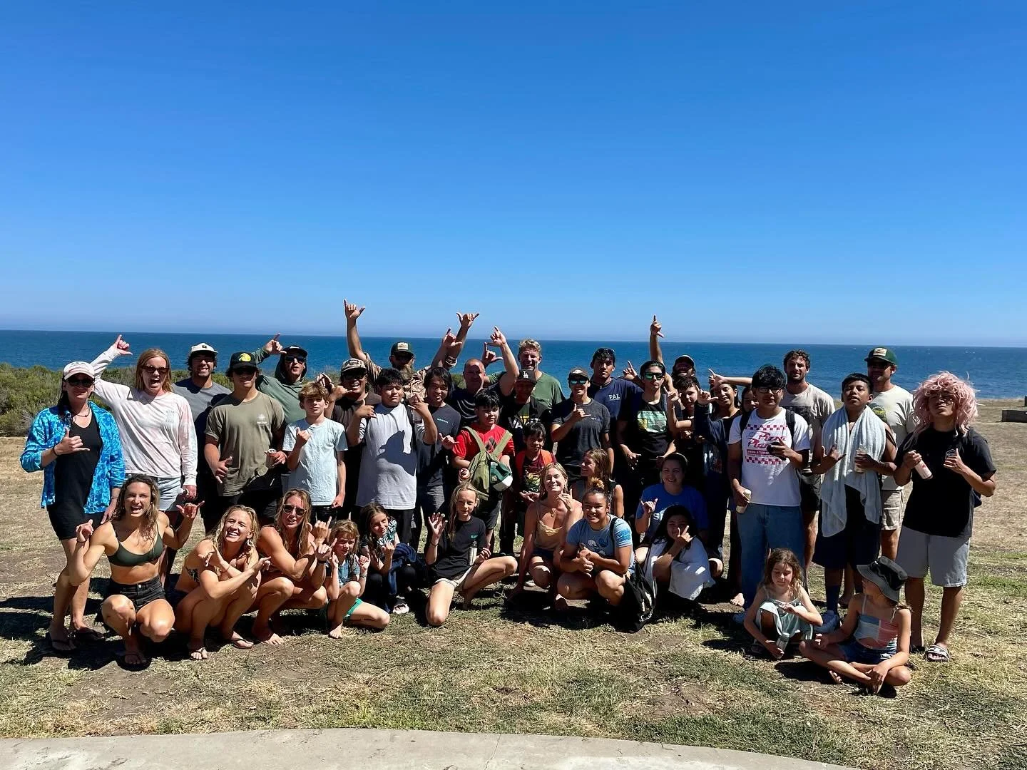 Large group of summer camp participants and staff posing together on an ocean overlook