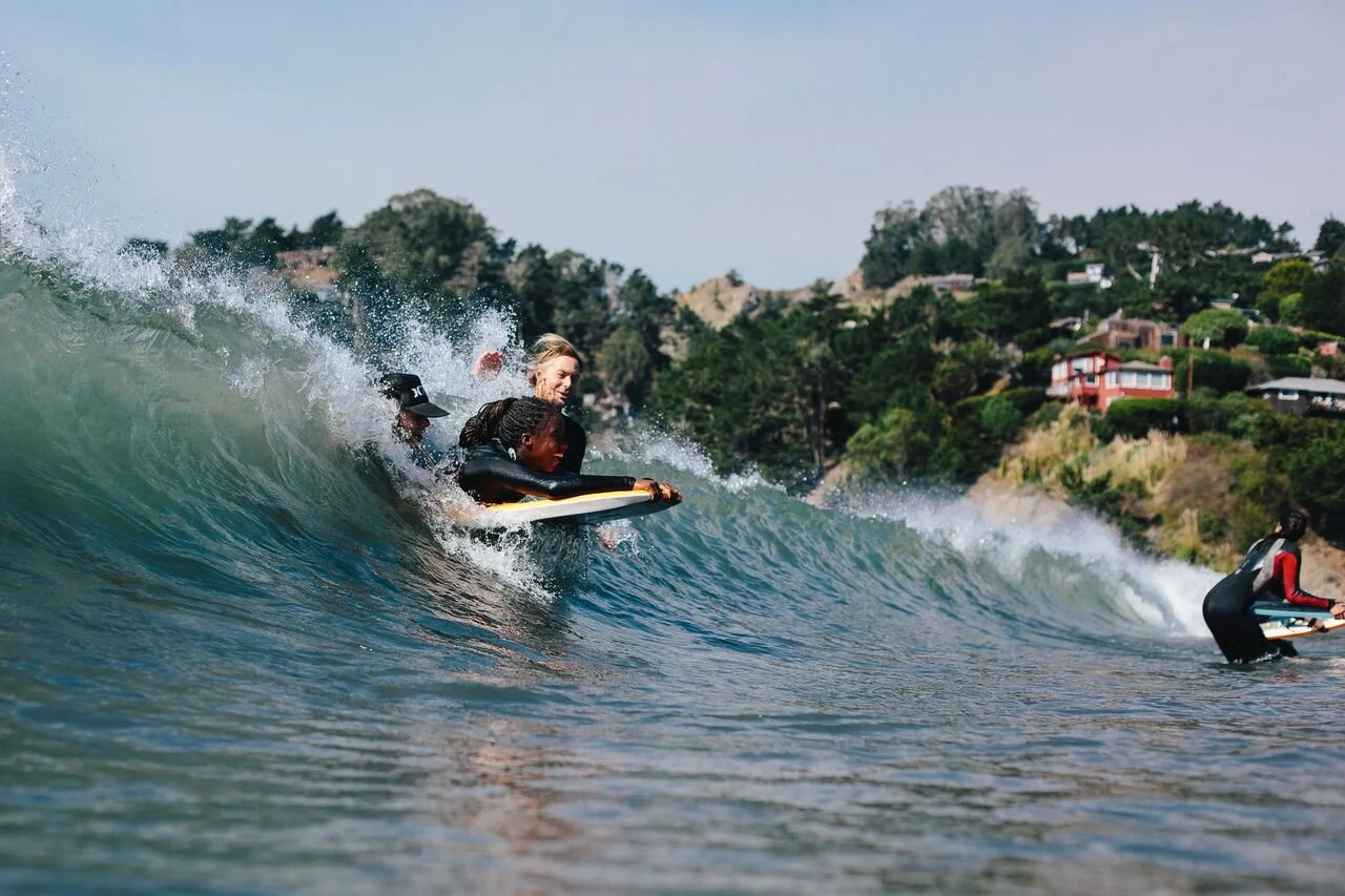 A young girl surfing into a curling wave with a female instructor alongside