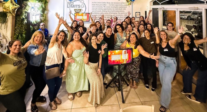 Large group of women cheering at a Miami Mom Collective community event inside No Limits Coffee Shop