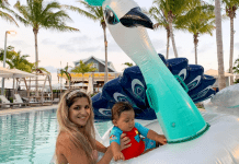 Woman and baby on a giant swan float in a resort pool with palm trees