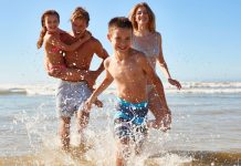 Family running and splashing in ocean waves on a South Florida beach