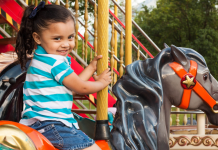 Young girl riding a carousel horse at a theme park