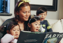 Mother reading to three children on a couch