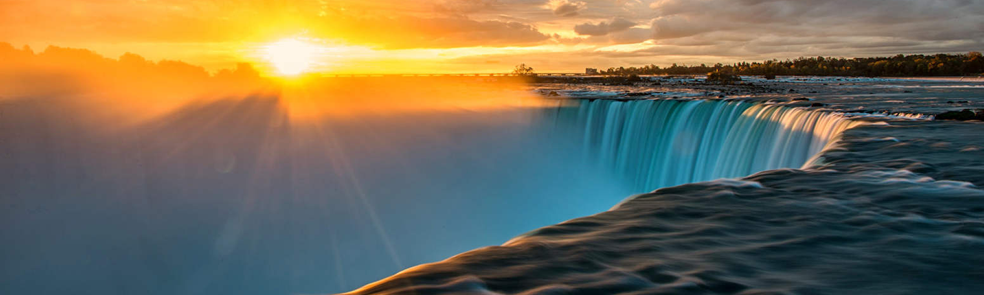 Niagara Falls at sunrise, golden sky over teal water