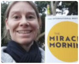 Woman outdoors holding The Miracle Morning book