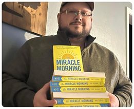 Man holding a stack of Miracle Morning books