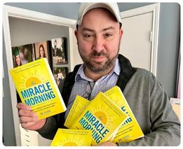 Man holding copies of The Miracle Morning