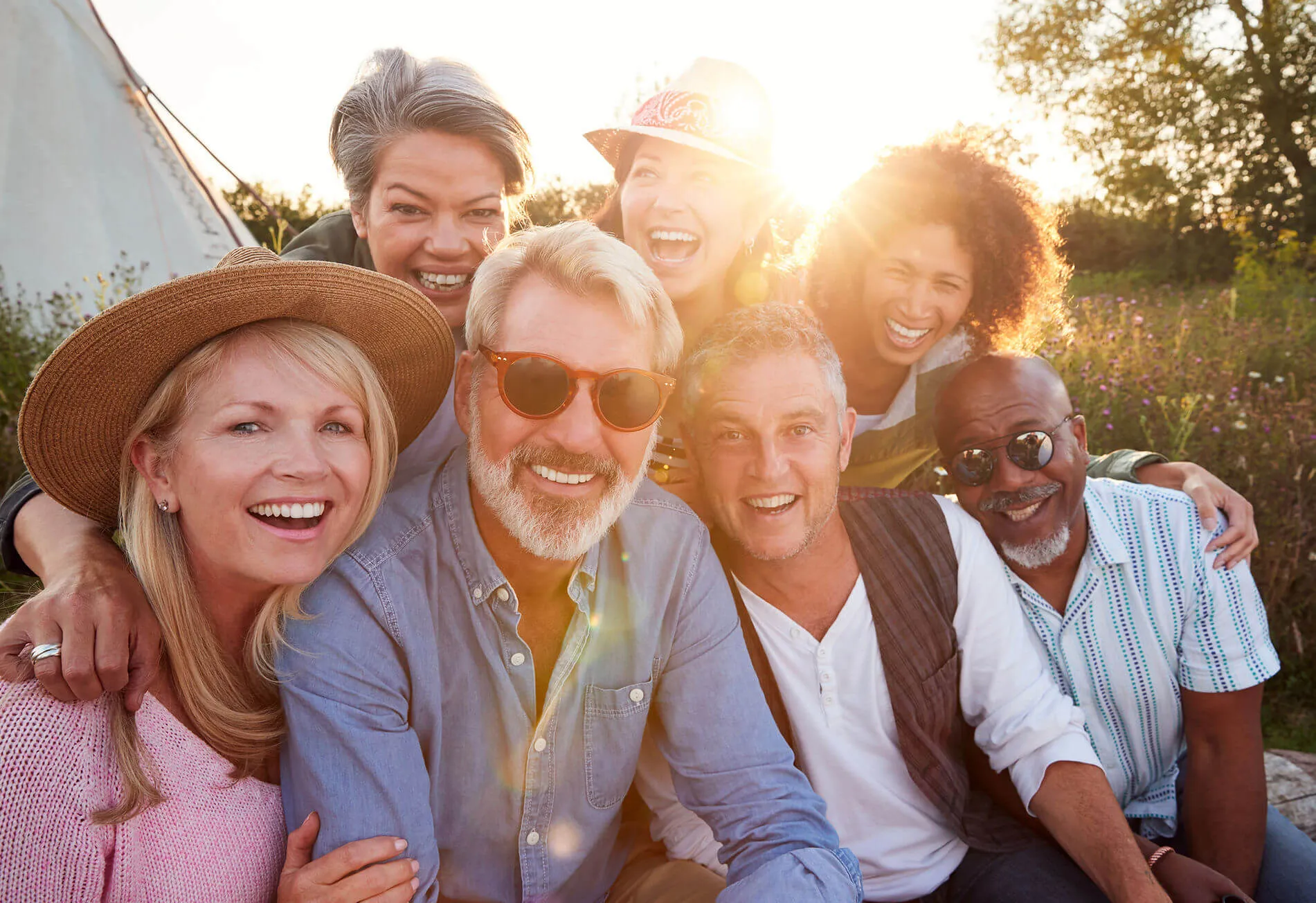A group of seven smiling friends together outdoors at golden-hour sunrise