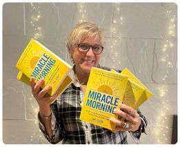 Woman with glasses holding two Miracle Morning books