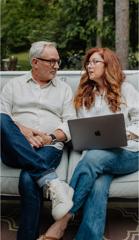 Founders Todd and Kristen Chatman sitting on an outdoor sofa reviewing a laptop together