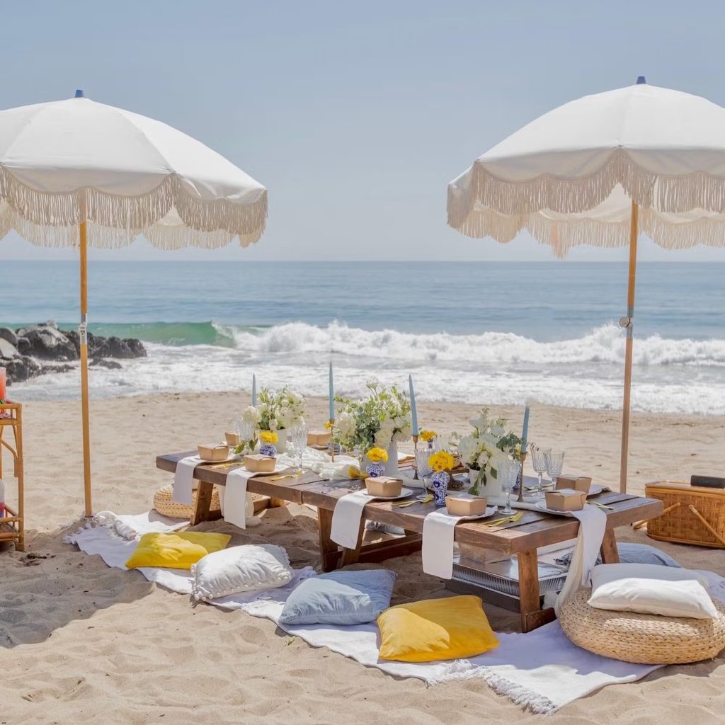 Styled beach picnic with fringe umbrellas and ocean backdrop