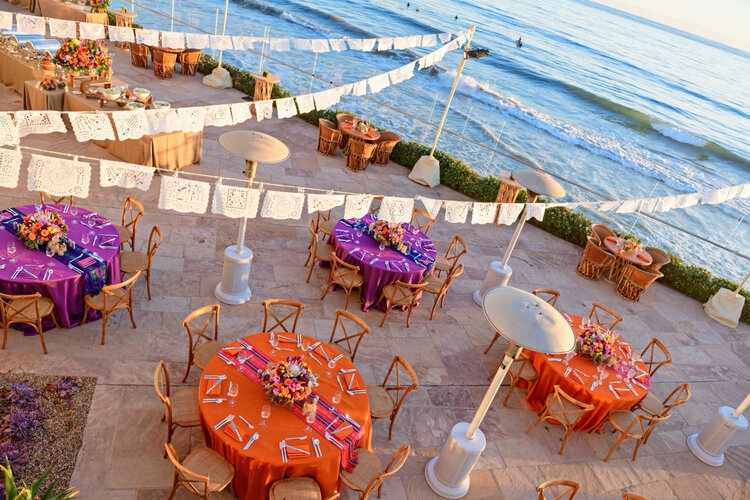 Fiesta-themed outdoor oceanfront dinner with colorful tablecloths and papel picado banners