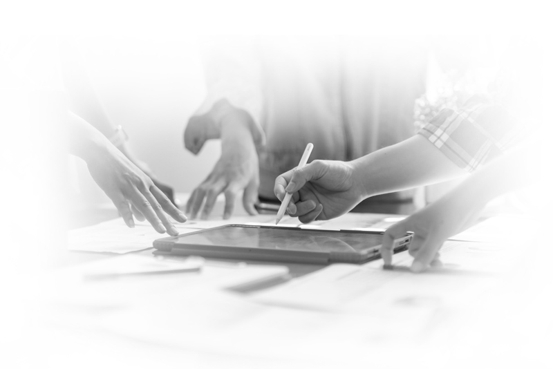 Hands collaborating over a tablet and documents