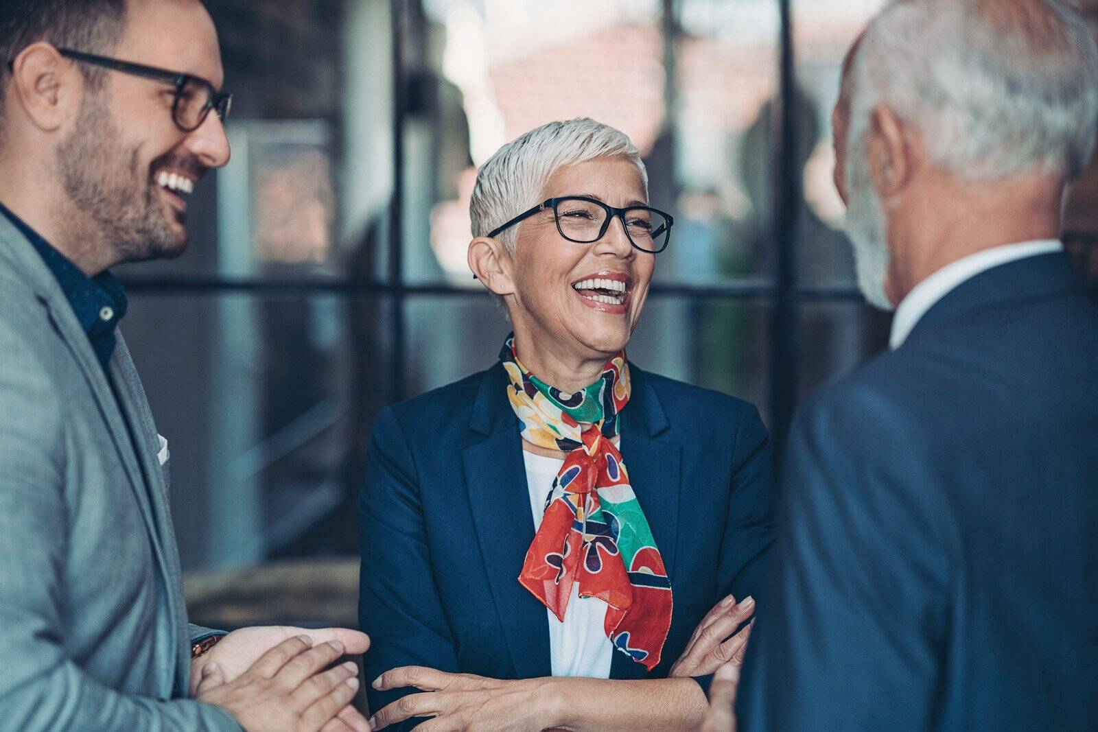 Three business professionals laughing together in a casual meeting