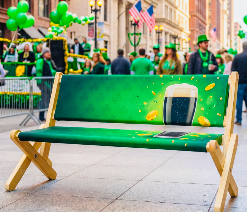 Green custom-printed wooden advertising bench with beer branding at a St. Patrick's Day parade