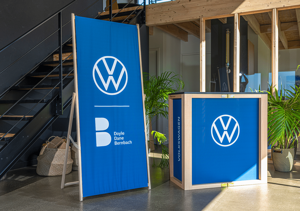 Volkswagen and Doyle Dane Bernbach branded folding wooden display easel and counter in a modern event space