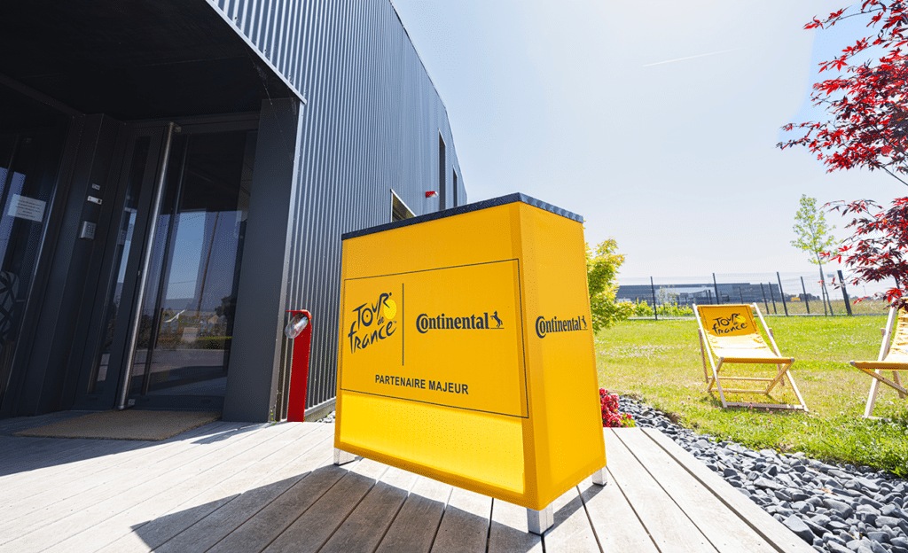 Yellow Tour de France and Continental branded folding wooden event counter with matching deckchairs behind