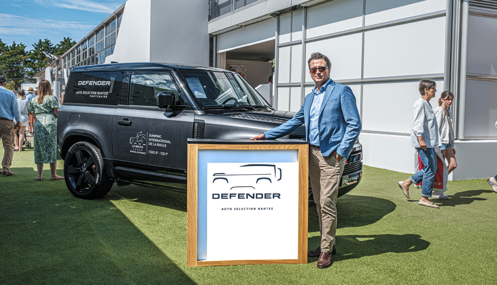 Defender-branded wooden trade-show counter with a presenter in a blazer at an outdoor event