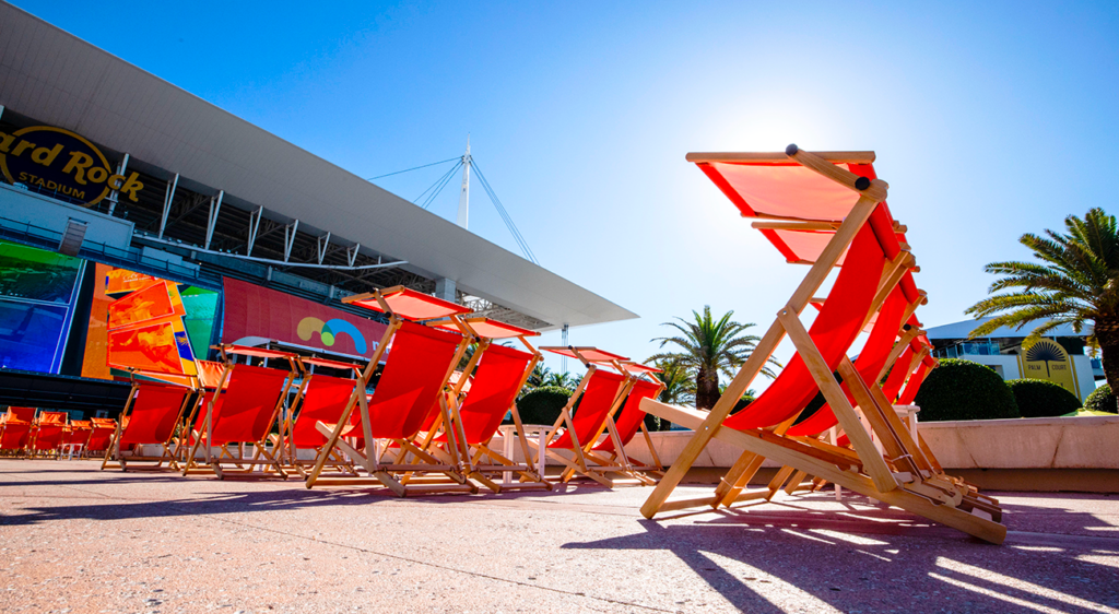 Row of red wooden deckchairs with canopies lined up outside Hard Rock Stadium in Miami