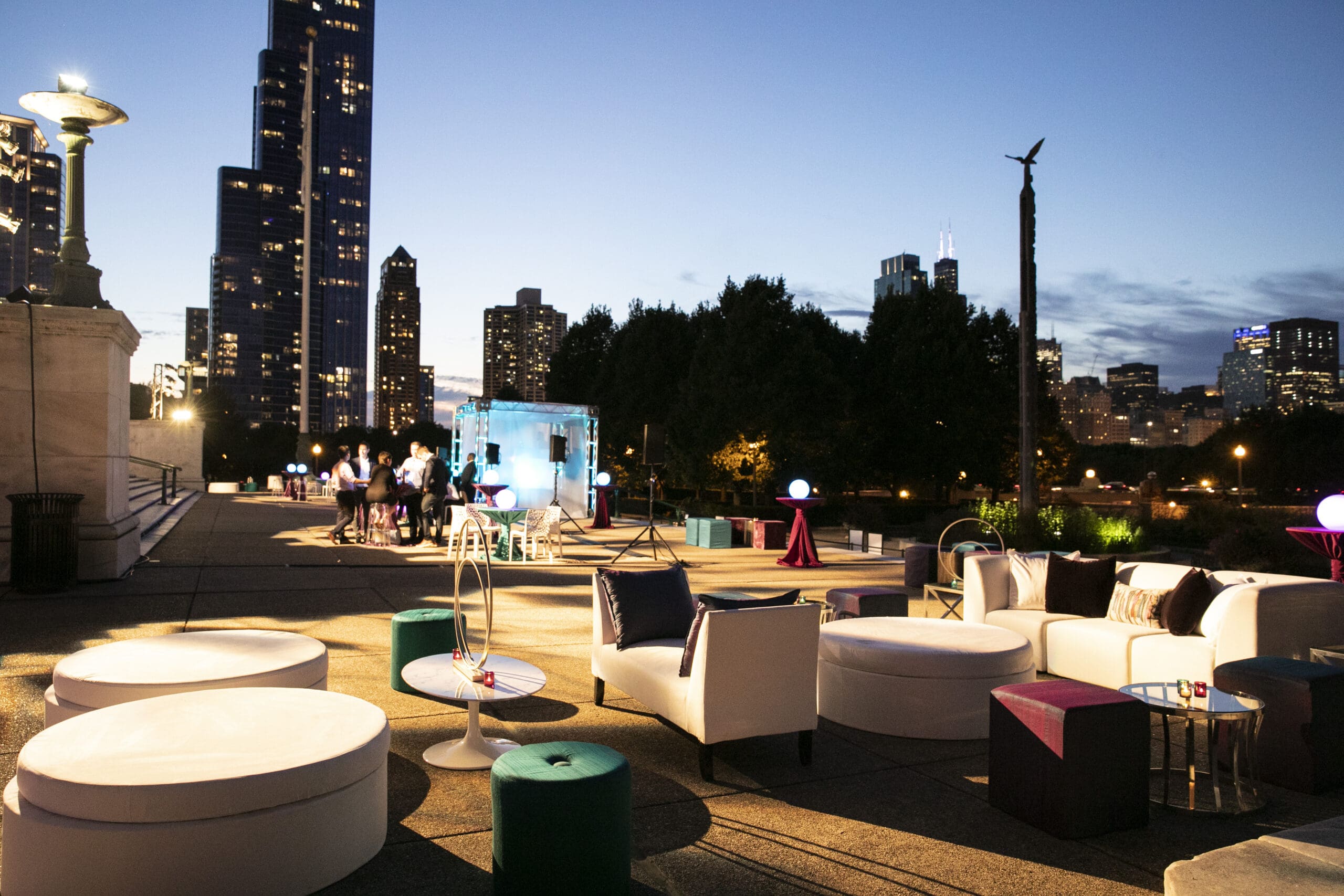 Outdoor rooftop event at dusk with the Chicago skyline, white lounge furniture and stage lighting