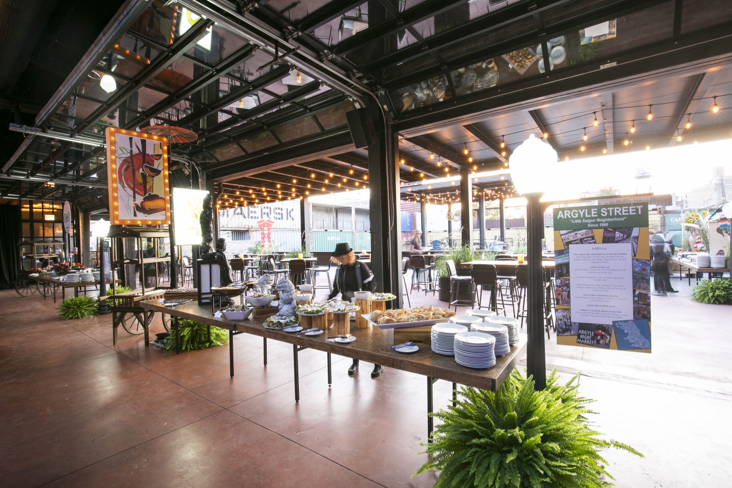 Themed corporate event styled as a Chicago Argyle Street night market with a buffet table and string lights