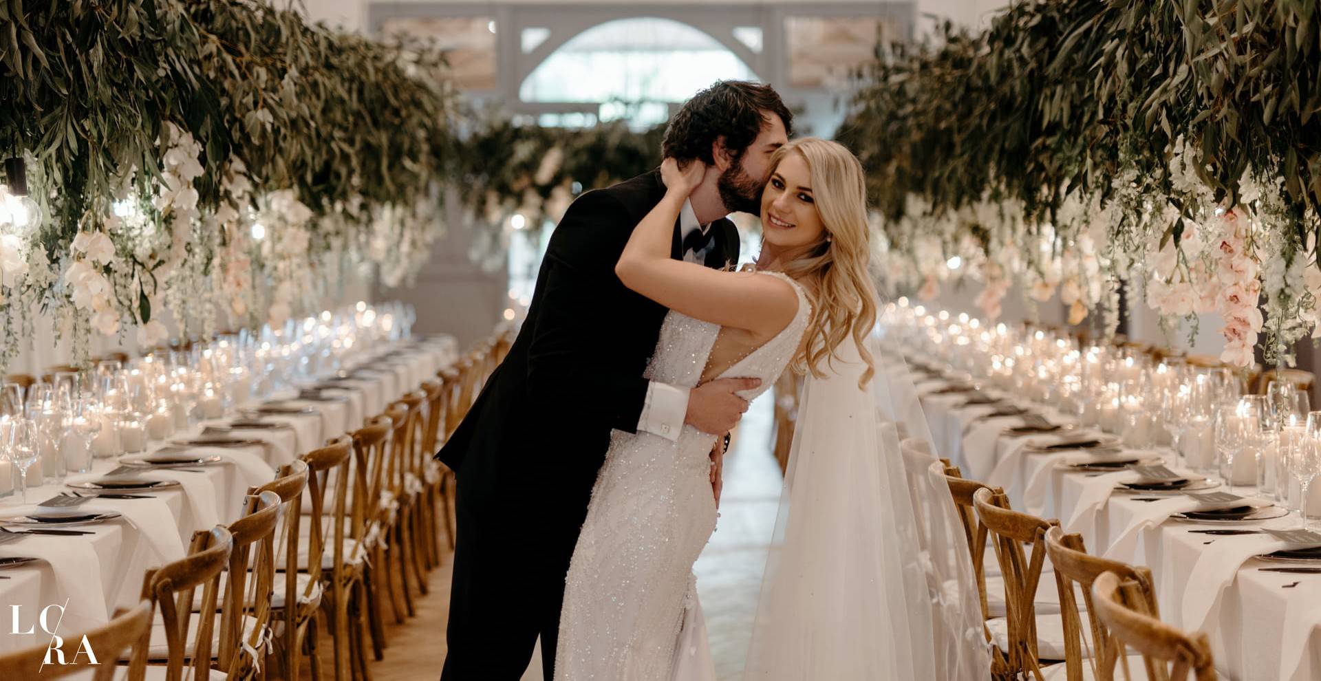 Bride and groom embracing in a lavish white floral reception hall